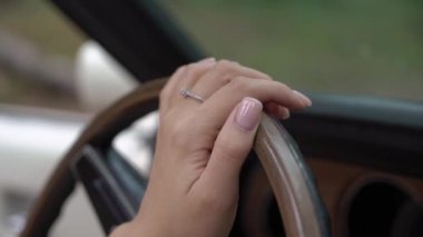 Genç kadın arabadaki tahta direksiyona dokunuyor. Kız sürücü.