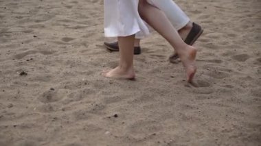 Genç ve romantik bir çift akşamüstü kumsalda yürüyor..