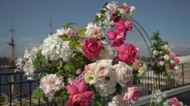 Dışarıda madalyalı bir düğün töreni. Beyaz ve pembe gül çiçekli kemer.