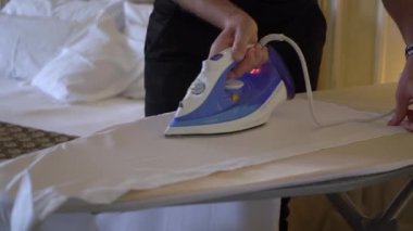 Üzerinde ütü olan klasik bir takım elbise için beyaz gömlek ütüleyen bir adam..