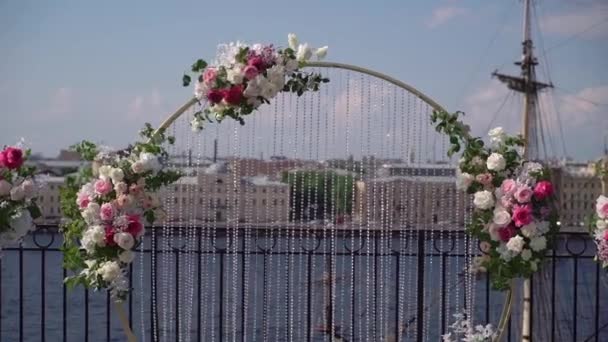 Dekorative Hochzeitszeremonie draußen. Bogen mit weißen und rosa Rosenblüten. — Stockvideo