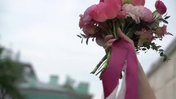 女性は手と波に花を持っている。ピンクと白の牡丹の花束. — ストック動画