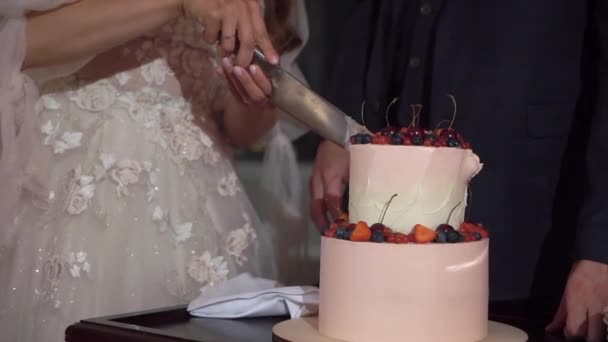 Ein Stück Hochzeitstorte anschneiden. Braut und Bräutigam mit Messer am Empfang. — Stockvideo