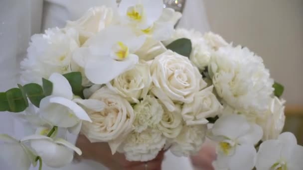 A bride in a wedding dress holds a bouquet of white flowers in her hands. — Stock Video