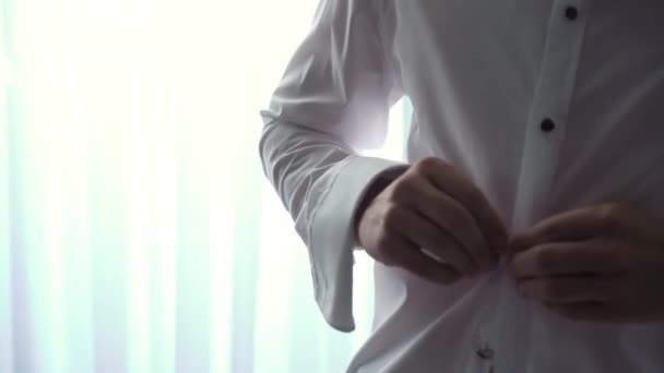 男は白いシャツを着てボタンを押す。結婚式の日の新郎の朝. — ストック動画