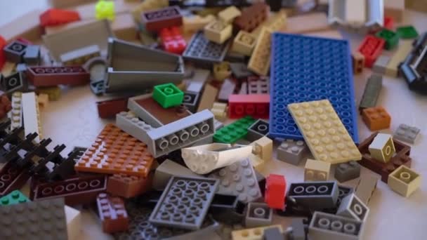 Piezas de Lego multicolores esparcidas sobre la mesa. Juguetes para niños, constructor. — Vídeo de stock