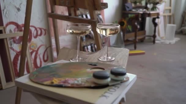 Junges Paar in der Kunstwerkstatt. Zwei Gläser Champagner. — Stockvideo