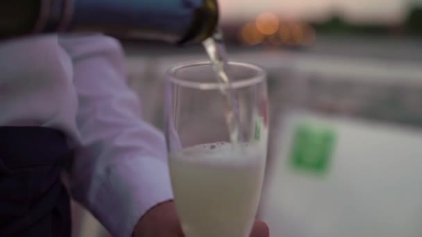 Наливание шампанского из бутылки в бокал на парусной яхте на закате вечером. — стоковое видео