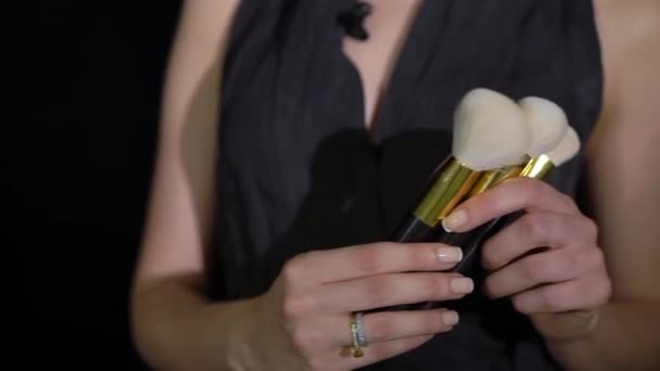 Joven mujer sostiene tres cepillos de maquillaje profesional en sus manos. — Vídeo de stock