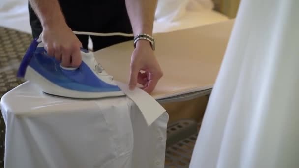 Hombre planchando una camisa blanca para un traje clásico con una plancha a bordo. — Vídeo de stock