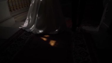 Gelin ve damat merdivenlerden iniyorlar. Düğün çifti el ele tutuşuyor..