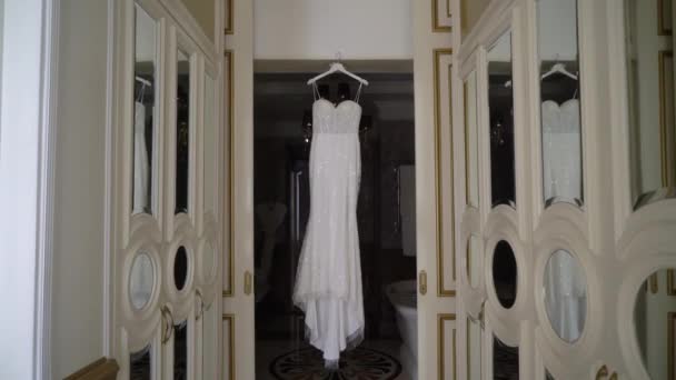 Wedding dress, white bridal gown hanging on hanger in bedroom. — Stock Video