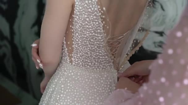 Domnișoara de onoare ajută mireasa să lege șireturi pe spatele rochiei de mireasă. — Videoclip de stoc