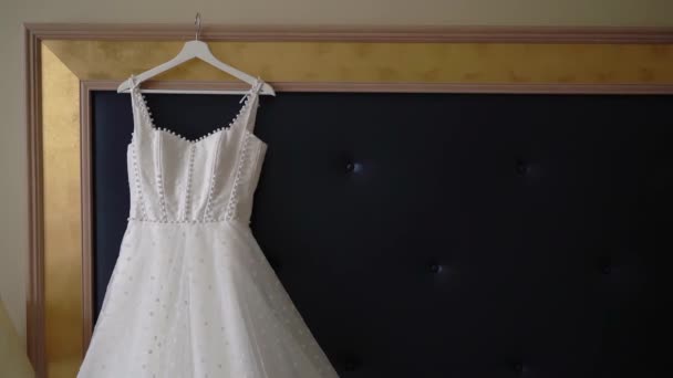 Νυφικό φόρεμα, λευκό νυφικό φόρεμα κρέμεται σε κρεμάστρα στην κρεβατοκάμαρα. — Αρχείο Βίντεο