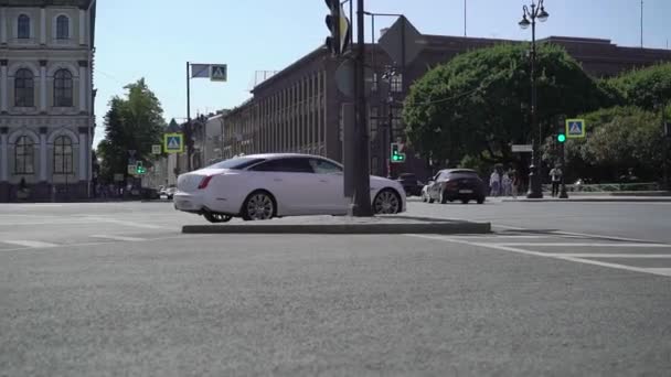Fehér luxus szedán Jaguar XJ hosszú autó vezetés a nyári városi úton. — Stock videók