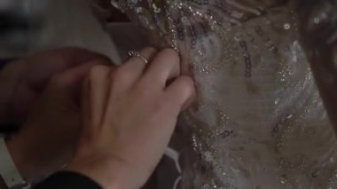 Nedime gelinin gelinliğinin arkasını bağlamasına yardım ediyor..