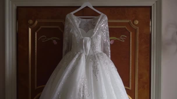 Hochzeitskleid, weißes Brautkleid hängt am Kleiderbügel im Schlafzimmer. — Stockvideo