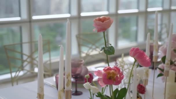 Table décorée au restaurant avec bougies, fleurs pivoines roses et roses blanches.