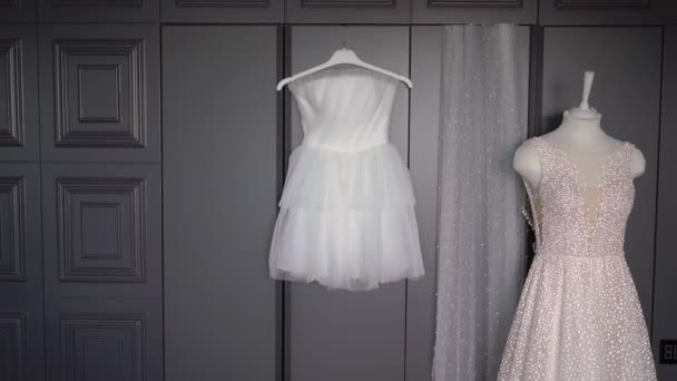 Dos vestidos de novia, vestido de novia blanco colgando de la percha en el dormitorio. Velo de novia. — Vídeos de Stock