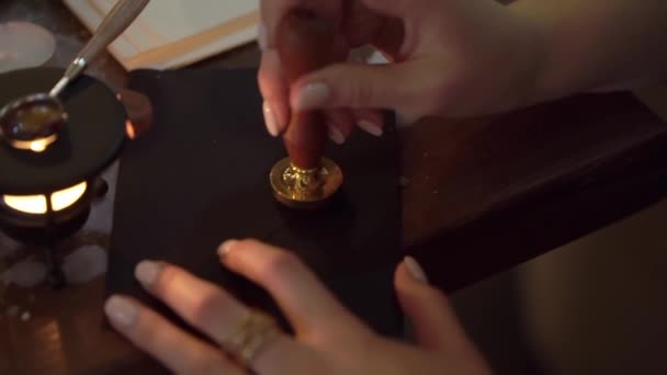 Girl seals the black envelope, fills it with red sealing wax, makes a seal. — Stockvideo