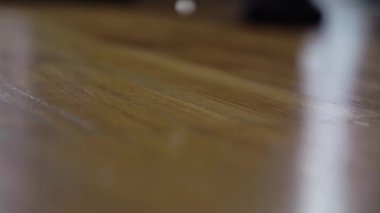 A white button from a shirt or other clothing comes off and falls on the floor.