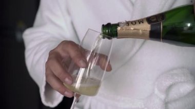 Man pours champagne to glass from MOET bottle. White sparkling wine.