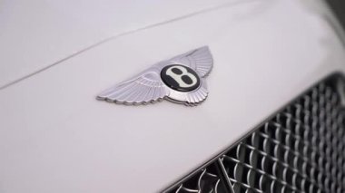 Bentley white luxury car logo on hood. Angel wings and B in circle. Front grill.