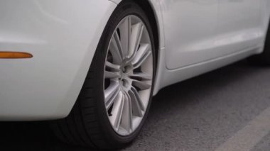 White luxury sedan Jaguar XJ long car driving in a city street.
