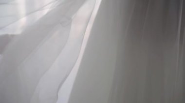 Gelinlik, pencerenin yanındaki yatak odasındaki askıya asılı. Gelinin sabahı.