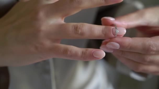Panna młoda zakłada obrączkę na palec. Obrączka ślubna w białym złocie z diamentem pod ręką. — Wideo stockowe