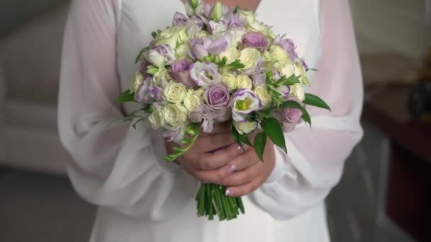 Une mariée dans une robe de mariée tient un bouquet de fleurs blanches dans ses mains.