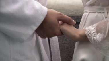 Young loving couple holding hands. Man and woman dressed in white robes.