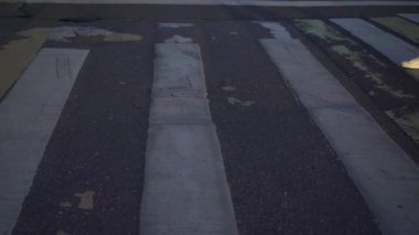 A young couple in white sneakers crosses the road at a pedestrian crossing.