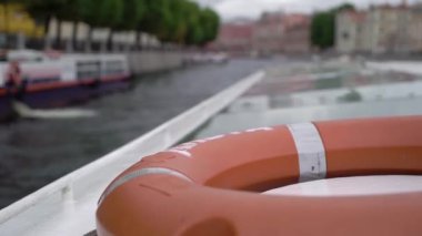 Sailing passenger touristic ship in a city. Lifebuoy, red inflatable ring.