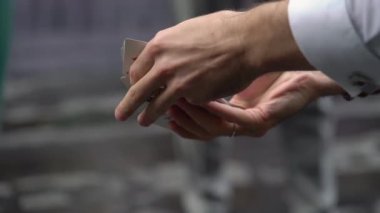 The magician shows a magic trick with cards. Male illusionist outdoor.