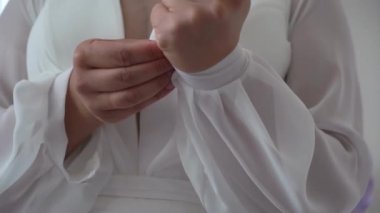 Gelin düğün gününde beyaz elbisenin kollarını ilikler..