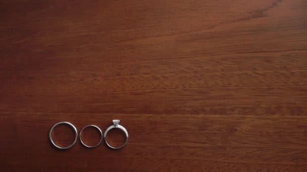 Wedding rings jewelry. Three gold rings on wooden background table. — Vídeo de Stock