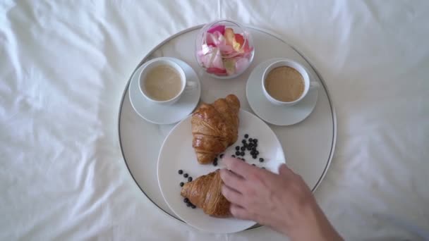 A man prepares breakfast for two. A cup of coffee or tea, croissants. — Stockvideo