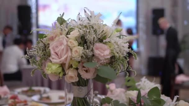 The brides bouquet on the table in the restaurant, people are dancing at party. — Wideo stockowe
