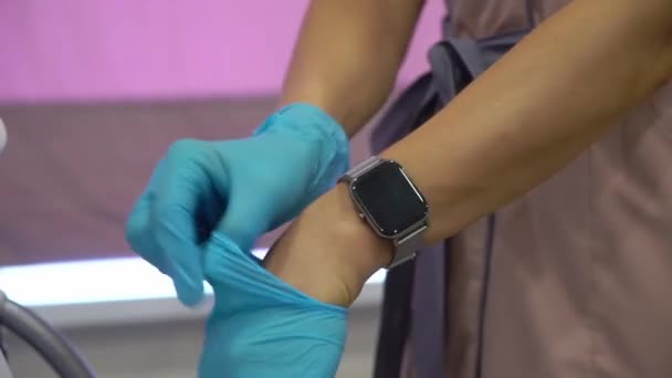 Woman doctor or nurse. Female is putting on blue medical protective gloves. — Stockvideo
