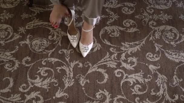 Bride wears wedding shoes with heels. Girl in wedding dress gets dressed. — Stockvideo
