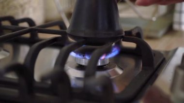 Coffee is brewed in a Turk on gas stove. Person cooking breakfast in the kitchen