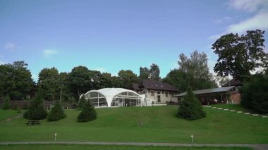White tent pavilion at green lawn on hill. Country restaurant in the hotel.