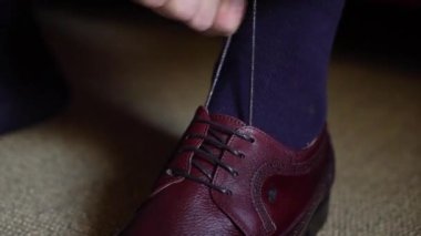 Adam ayakkabılarını giyer. Beyaz gömlekli bir erkek çizmelerini elinde tutuyor..