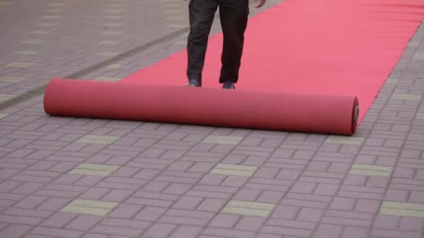 Чоловік викидає червоний килим на святкування . — стокове відео