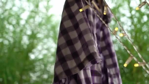 Wet clothes dry in the wind and sun after washing. A white-violet plaid shirt. — Stock video