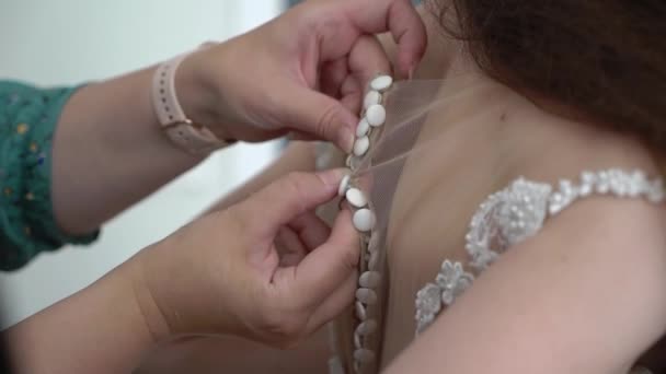 Druhna pomaga pannie młodej zapiąć guziki z tyłu sukni ślubnej. — Wideo stockowe