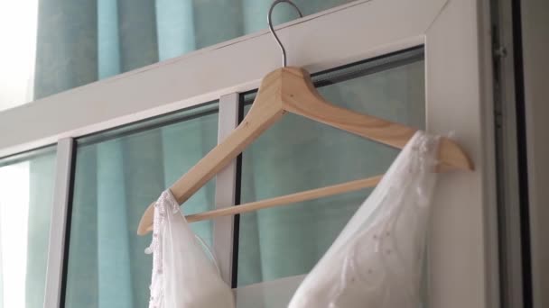 웨딩 드레스는 침실 창문 옆의 옷걸이에 걸려 있다. 신부가 가운을 입다. — 비디오