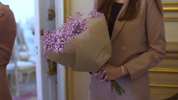 A young woman holds a gift festive bouquet of pink small flowers. — стоковое видео