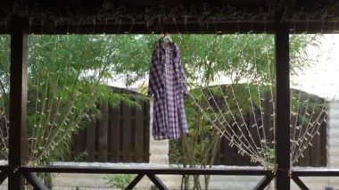 Wet clothes dry in the wind and sun after washing. A white-violet plaid shirt.